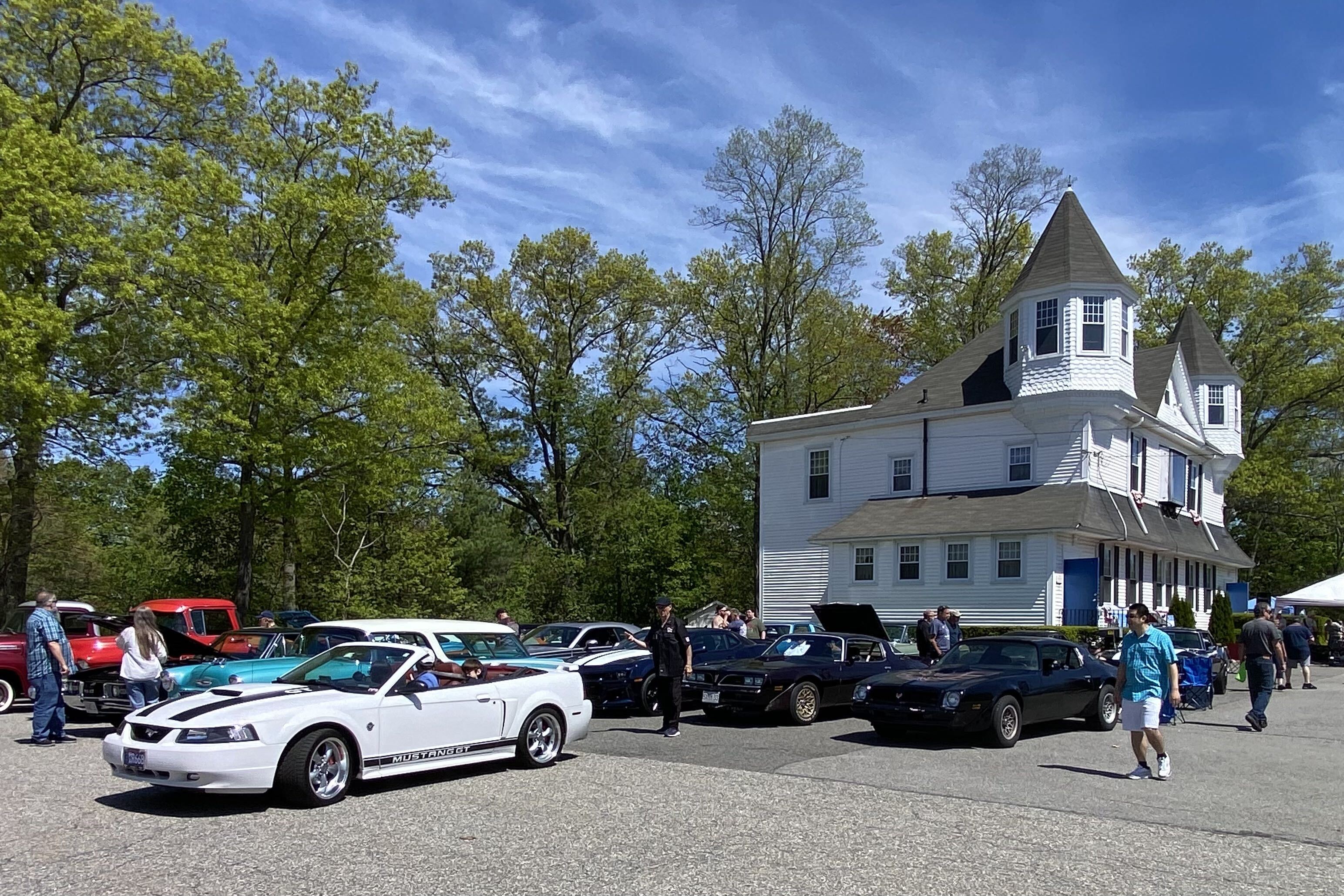Classic cars and visitors gathered outside Friendship Lodge during a community car show